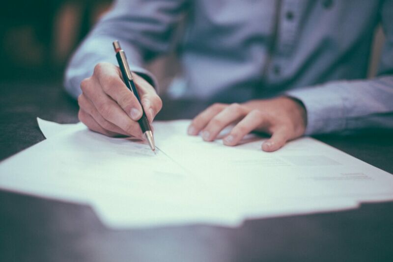 man writing project documents with pen